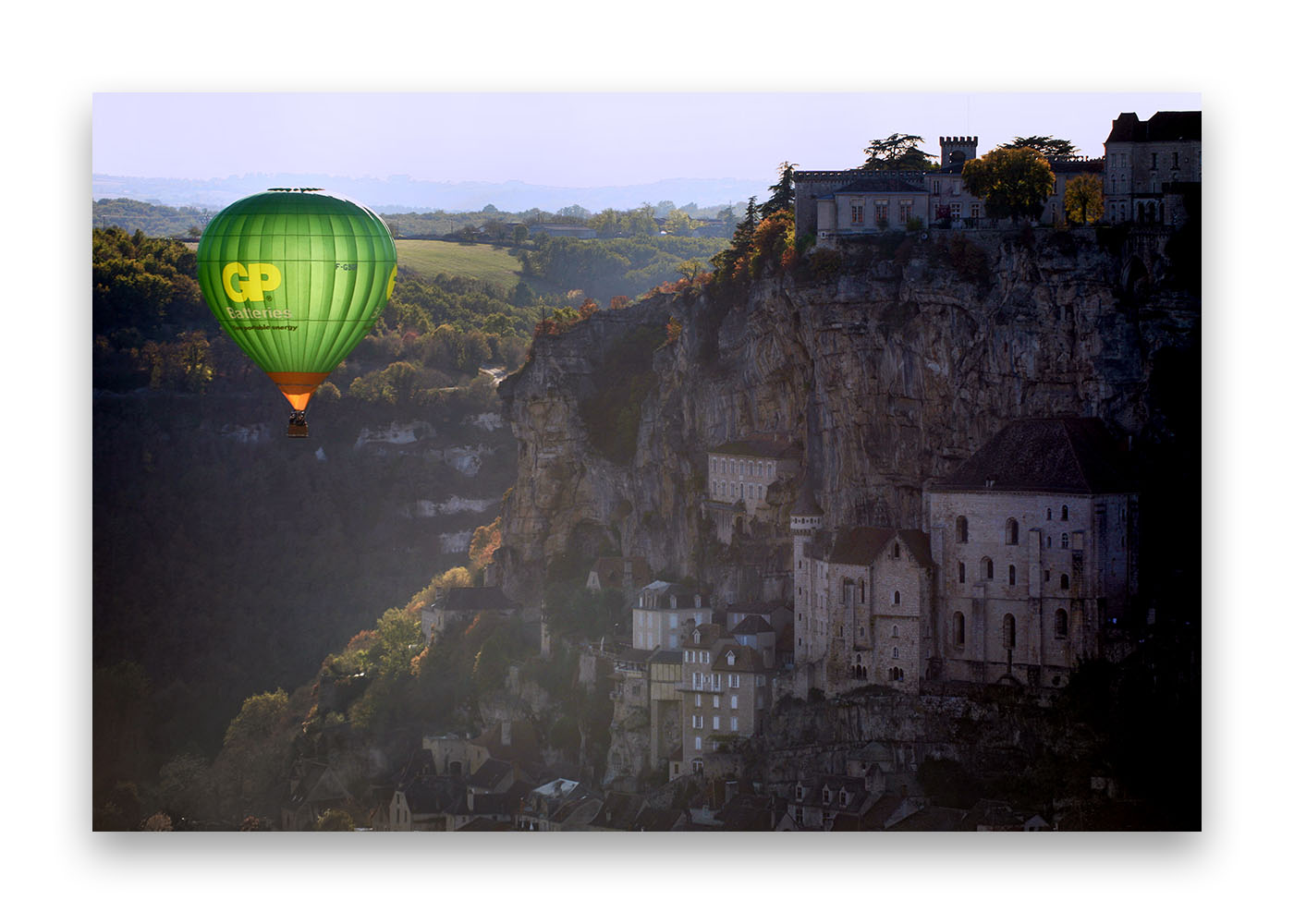 Une montgolfière  en premier pan face à Rocamadour sous une lumière de fin de journée.