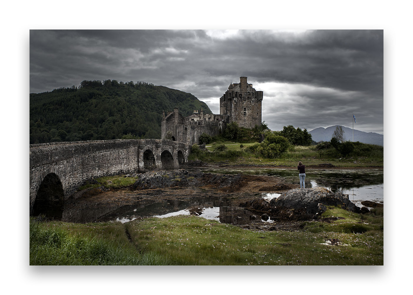 Une photographe de dos sur un rocher face au château Eilean Donan , le plus célèbre château écossais.