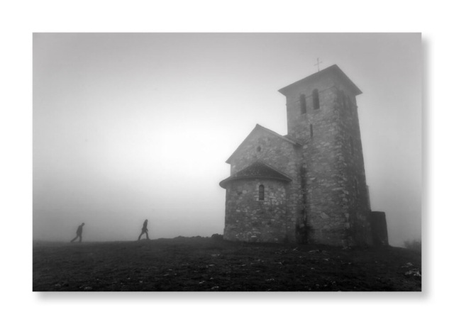 Deux personnes marchent en direction d une chapelle dans le brouillard