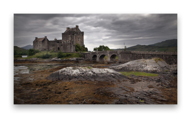 Une vue du Château Eilean Donan  en  Écosse avec en premier plan un rocher a marée basse.